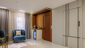 A modern living room with a blue armchair, a small coffee table, a beige ottoman, a minibar, and a wardrobe with vertical lines. - 3 bedroom apartment (Giza Governorate)