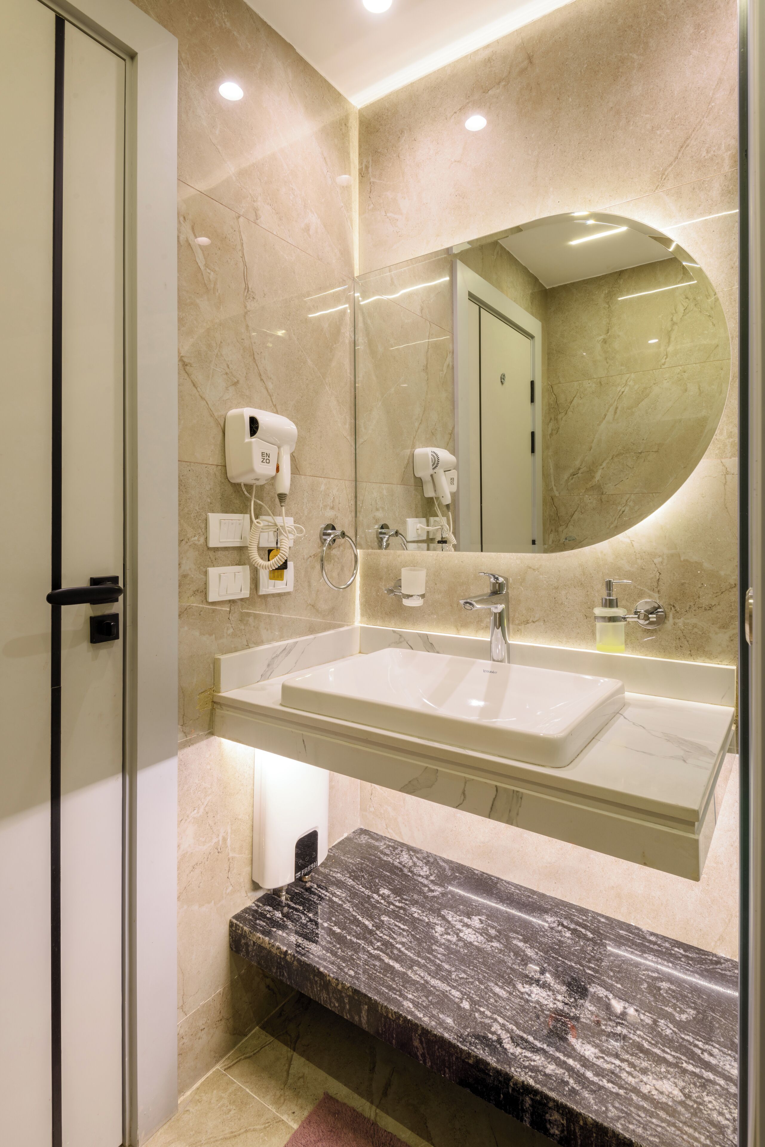 Un baño moderno con un espejo grande, lavamanos doble y un secador de pelo en la pared.