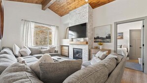 A modern living room with a stone fireplace, a large flat-screen TV, and a cozy seating area. - Beautiful updated Villa w/ Resort Amenities + Holistic Body Services Villa 3023-1 (Midway)
