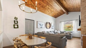A cozy living room with a wooden ceiling, a grey sofa, a dining table with chairs, and artwork on the walls. - Beautiful updated Villa w/ Resort Amenities + Holistic Body Services Villa 3023-1 (Midway)
