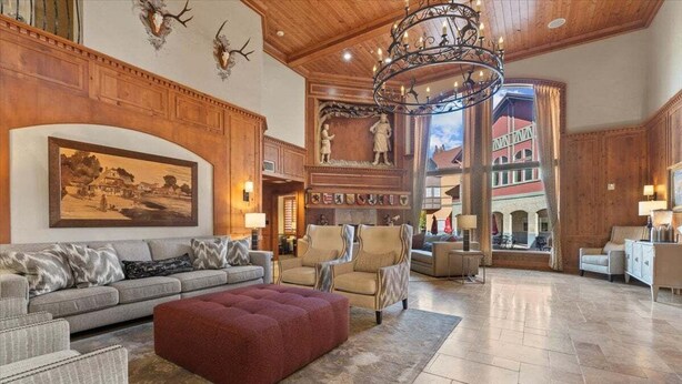 A spacious lobby with a high ceiling, wooden paneling, a large chandelier, and a view of a red building through an open archway. - Updated Villa w/ Resort Amenities + Holistic Body Services Villa 3021-Q (Midway)