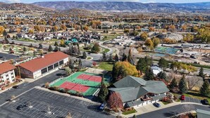 An aerial view of a residential area with houses, a tennis court, and a parking lot. - Updated Villa w/ Resort Amenities + Holistic Body Services Villa 3021-Q (Midway)