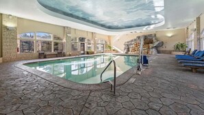 An indoor swimming pool with stone flooring, a rock wall, and a glass ceiling. - Updated Villa w/ Resort Amenities + Holistic Body Services Villa 3021-Q (Midway)