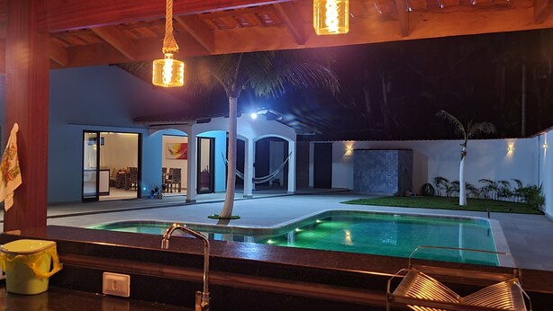 Een zwembad met een whirlpool, een houten terras en uitzicht op het interieur van het gebouw.
