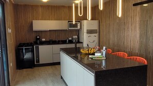 Een moderne keuken met een centraal eiland, houten lambrisering en hangende lampen.