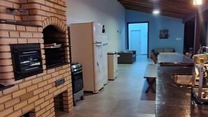 Een keuken met een bakoven, een koelkast, en een eethoek met een tafel en stoelen.