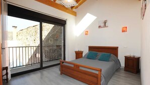 Une chambre avec un lit en bois, un balcon et un mur en pierre à l’extérieur.