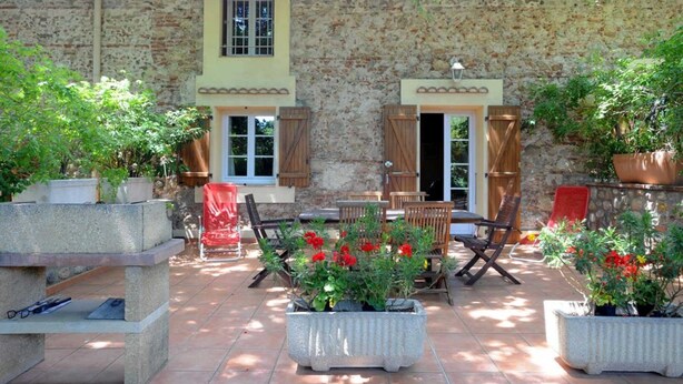 A stone building with a patio area featuring outdoor furniture and potted plants. - La tramontane - ELNE (ELNE)
