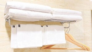 Ein Badezimmer mit Handtuchhalter, der gefaltete Handtücher und einen Holzaufhänger trägt.