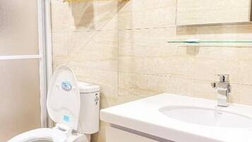 Ein Badezimmer mit Toilette, Waschbecken und einem Glastischchen darüber.