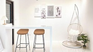 Eine moderne Küche mit zwei Barhocker, einem Hängesessel und einem Blumentopf.
