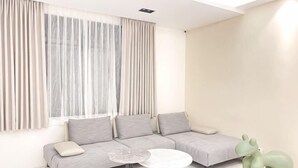 Ein modernes Wohnzimmer mit einer Eckcouch, einem kleinen runden Tisch und einem grünen Sessel in Tierform.