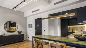 A modern kitchen with a central island, bar stools, and a round mirror on the wall.