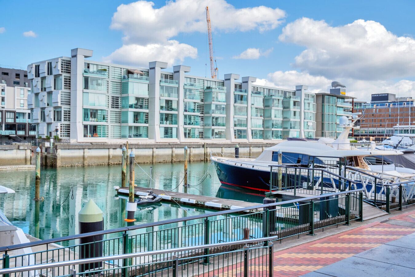 A marina with modern buildings, a docked boat, and a clear sky.