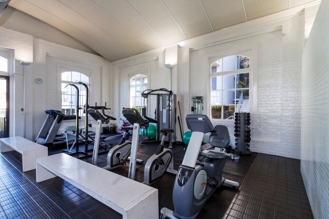 Ein Fitnessstudio mit Laufbändern, Crosstrainern und Gewichten.