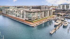 Un hôtel moderne à plusieurs étages, offrant une vue sur le front de mer, avec des bateaux amarrés et un port de plaisance.