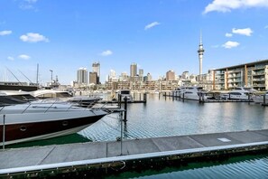 A marina with yachts docked, a city skyline in the background, and a prominent tower. - Lighter Quay - Calm & Well-Appointed Pool & Gym (Auckland)