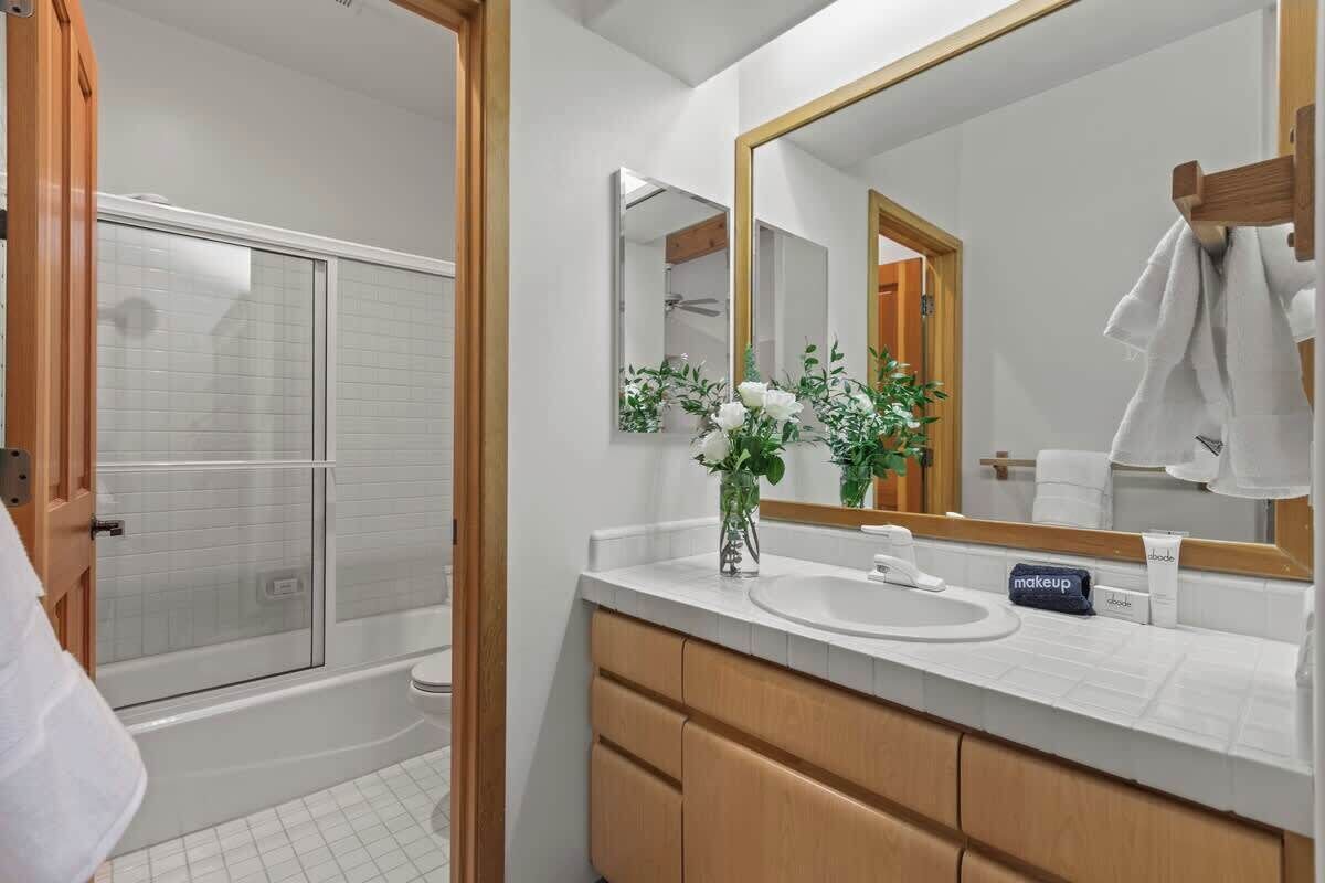 Een moderne badkamer met een douche, een wastafel met spiegel en een bloevas.