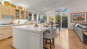 A modern kitchen with a central island, wooden flooring, and large windows. - Abode at Sawtooth, chef's kitchen, sleeps 10, near ski resort (Sun Valley)