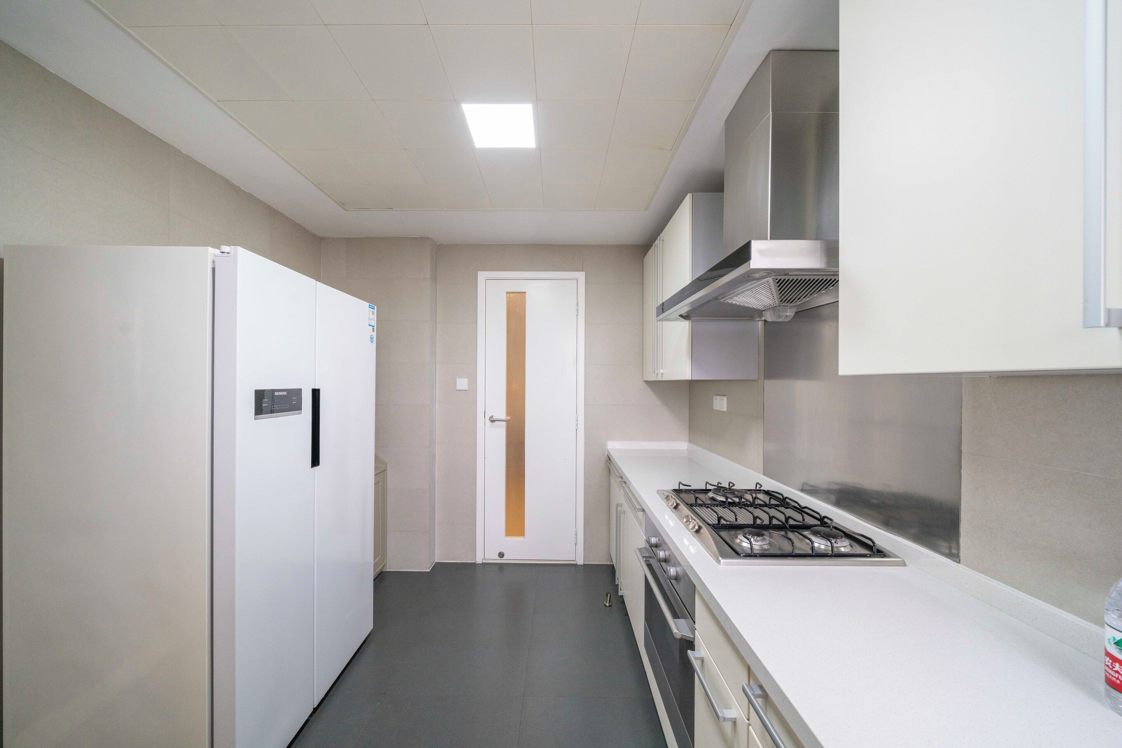 A modern kitchen with a white refrigerator, oven, and gas stove.