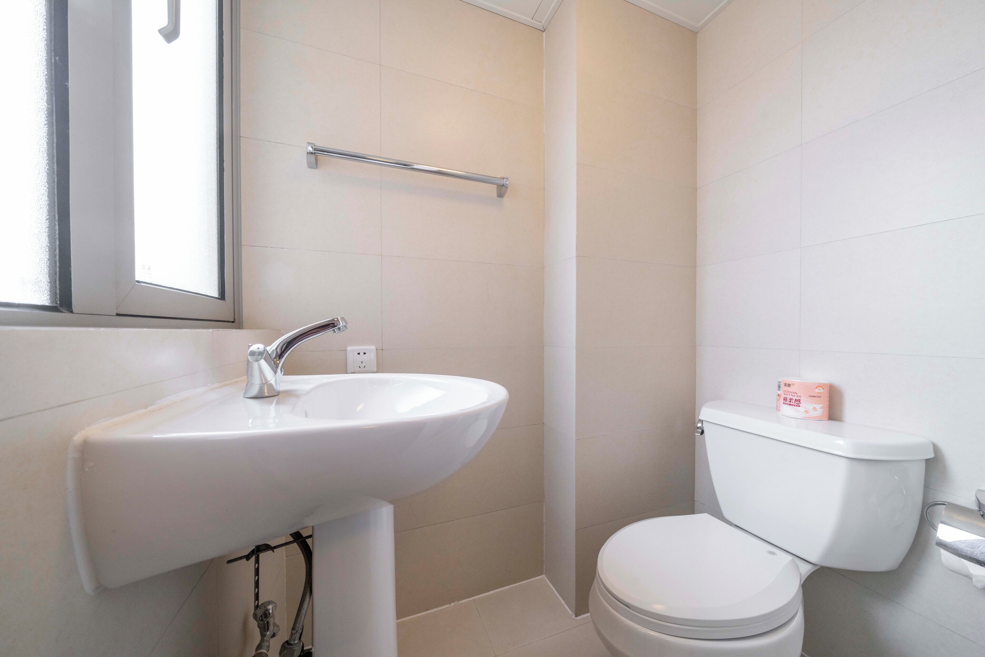 A bathroom with a white sink, a toilet, and a window.