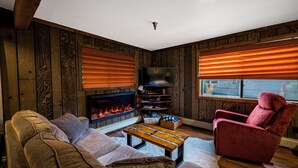 En hyggelig stue med pejs, en rød lænestol og en sofa.
