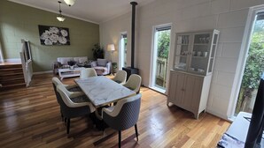 Un vaste espace de vie comprenant une table et des chaises, un canapé, un meuble avec des portes en verre et un escalier menant à un autre niveau.