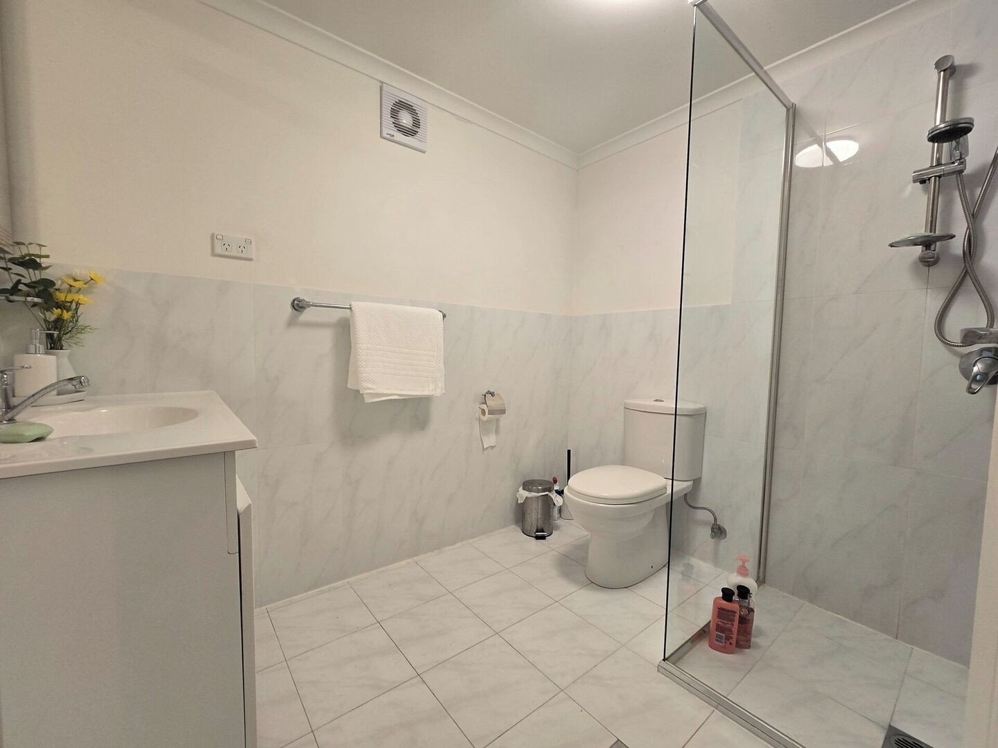 Ein modernes Badezimmer mit Duschkabine aus Glas, einer weißen Toilette und einem Waschbecken mit Spiegel.
