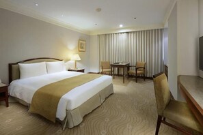 A hotel room with a large bed, a desk, two chairs, a television, and a window with curtains. - Lemidi Hotel (Taoyuan)