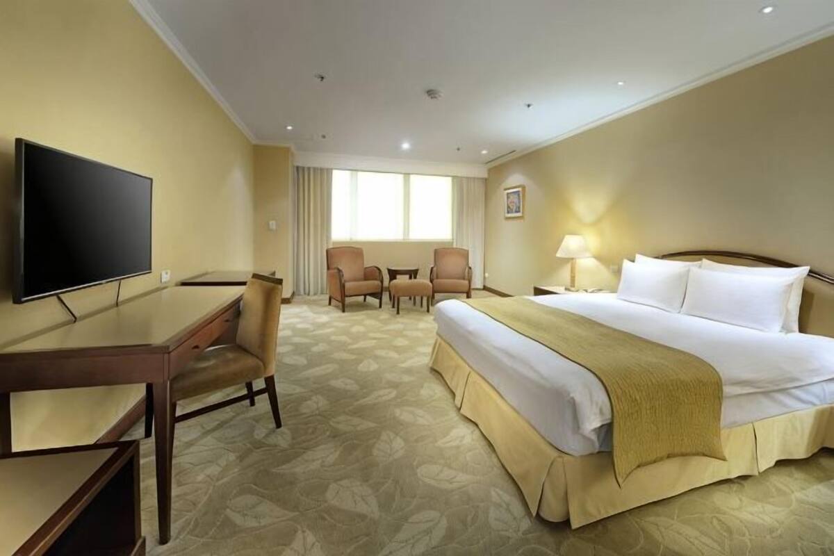 Una habitación de hotel con una cama, un escritorio, un televisor y dos sillas.