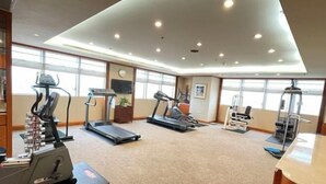 Une salle de sport équipée de tapis de course, de vélos elliptiques et d'appareils de musculation.