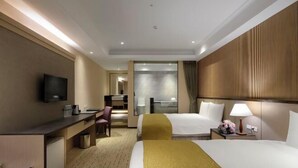 Une chambre d’hôtel équipée d’un lit, d’un bureau, d’une chaise, d’une télévision et d’une petite kitchenette.