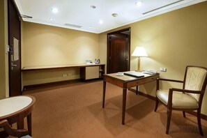 Una habitación de hotel con una cama, un escritorio, una silla, una lámpara y una pequeña mesa.