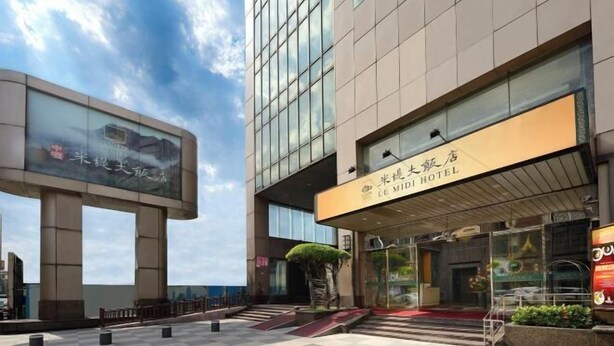 Un hôtel moderne doté d’une entrée imposante, de grandes fenêtres et d’un espace paysager agrémenté d’un petit arbre.
