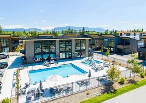 Ein modernes Hotel mit Schwimmbad, Liegestühlen und Bergblick.