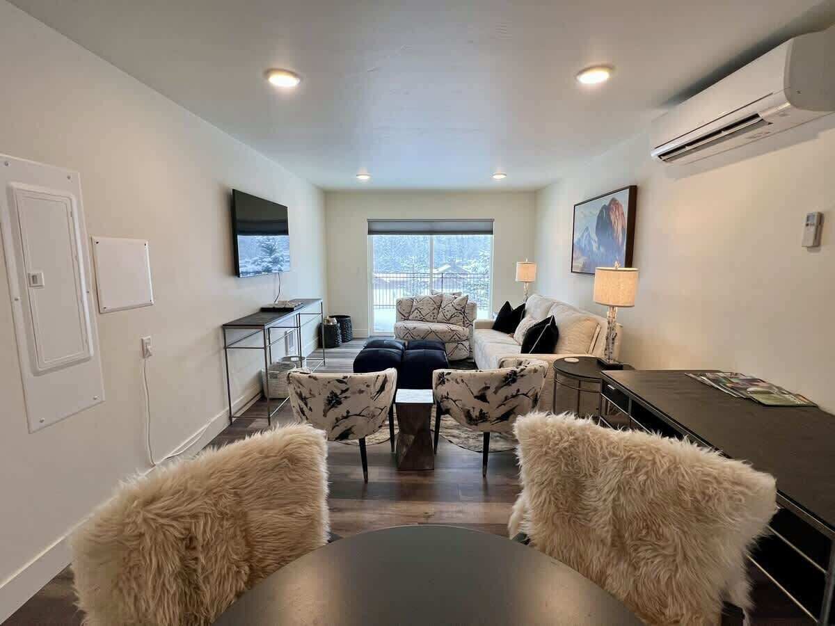 Un salon moderne comprenant un canapé, deux fauteuils, une table basse et un téléviseur.
