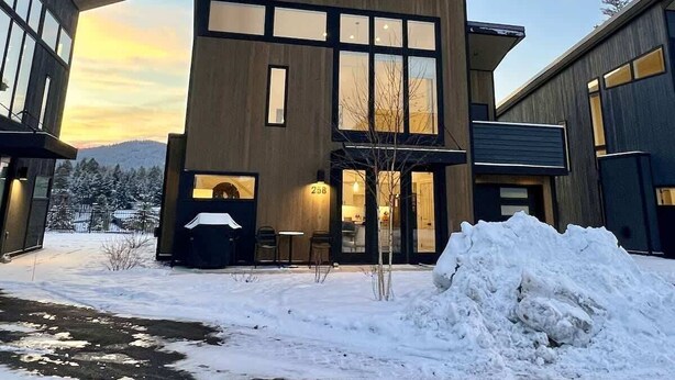 Um edifício moderno de dois andares com grandes janelas e teto plano, rodeado por neve.