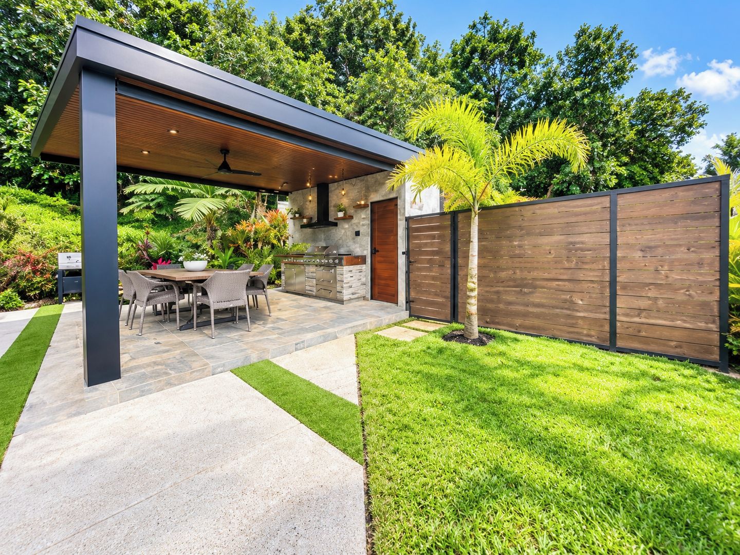 Un área de cocina exterior moderna con comedor, una parrilla y un pérgola.
