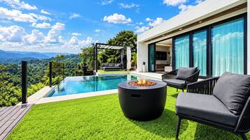 A modern outdoor pool area with a fire pit, seating, and a view of the mountains.