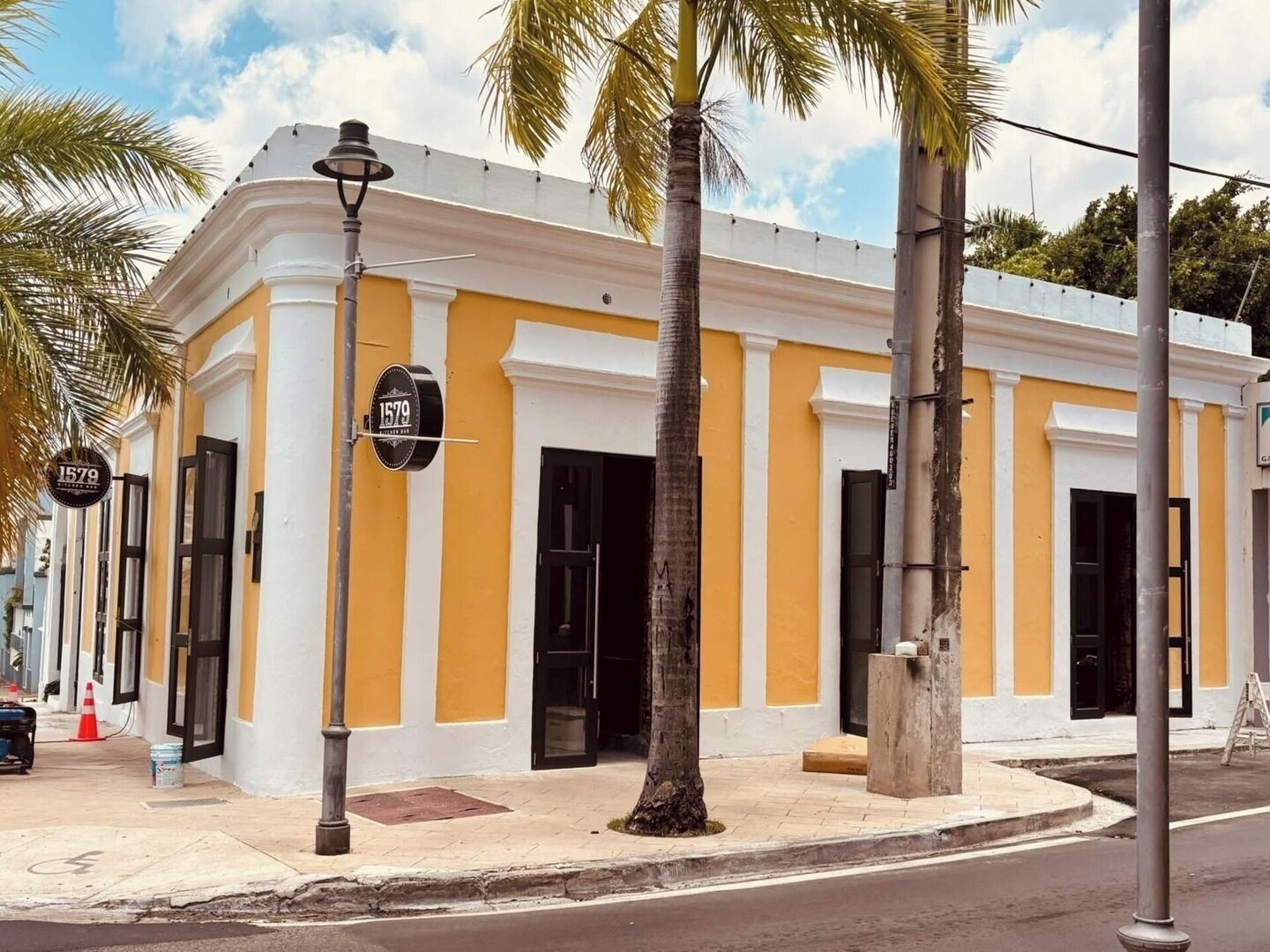 Un edificio con fachada amarilla, puertas negras y una farola.