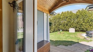 Une véranda couverte avec un plafond en bois et une porte en verre.