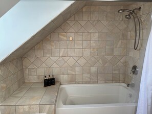 Une salle de bain avec une baignoire, une douche et des murs carrelés.