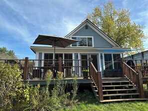 Une maison à deux étages avec un porche couvert, un escalier en bois et un grand parasol.