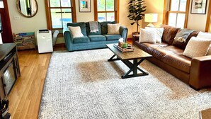 Un salon avec un canapé bleu, un canapé en cuir marron, une table basse, une plante et une cheminée.