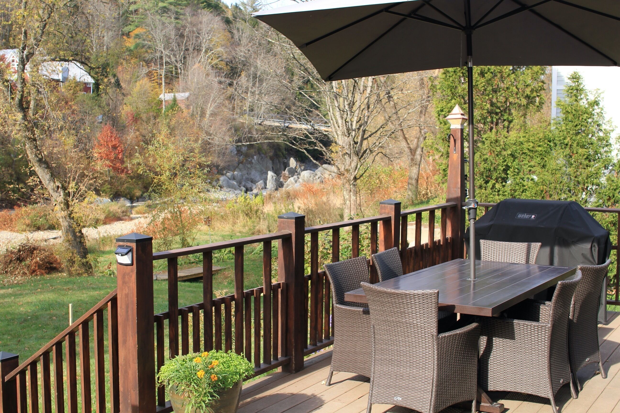 Une terrasse extérieure avec une table et des chaises, un barbecue et une clôture en bois.