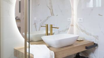 A modern bathroom with a large oval mirror, a vessel sink, and a gold faucet.