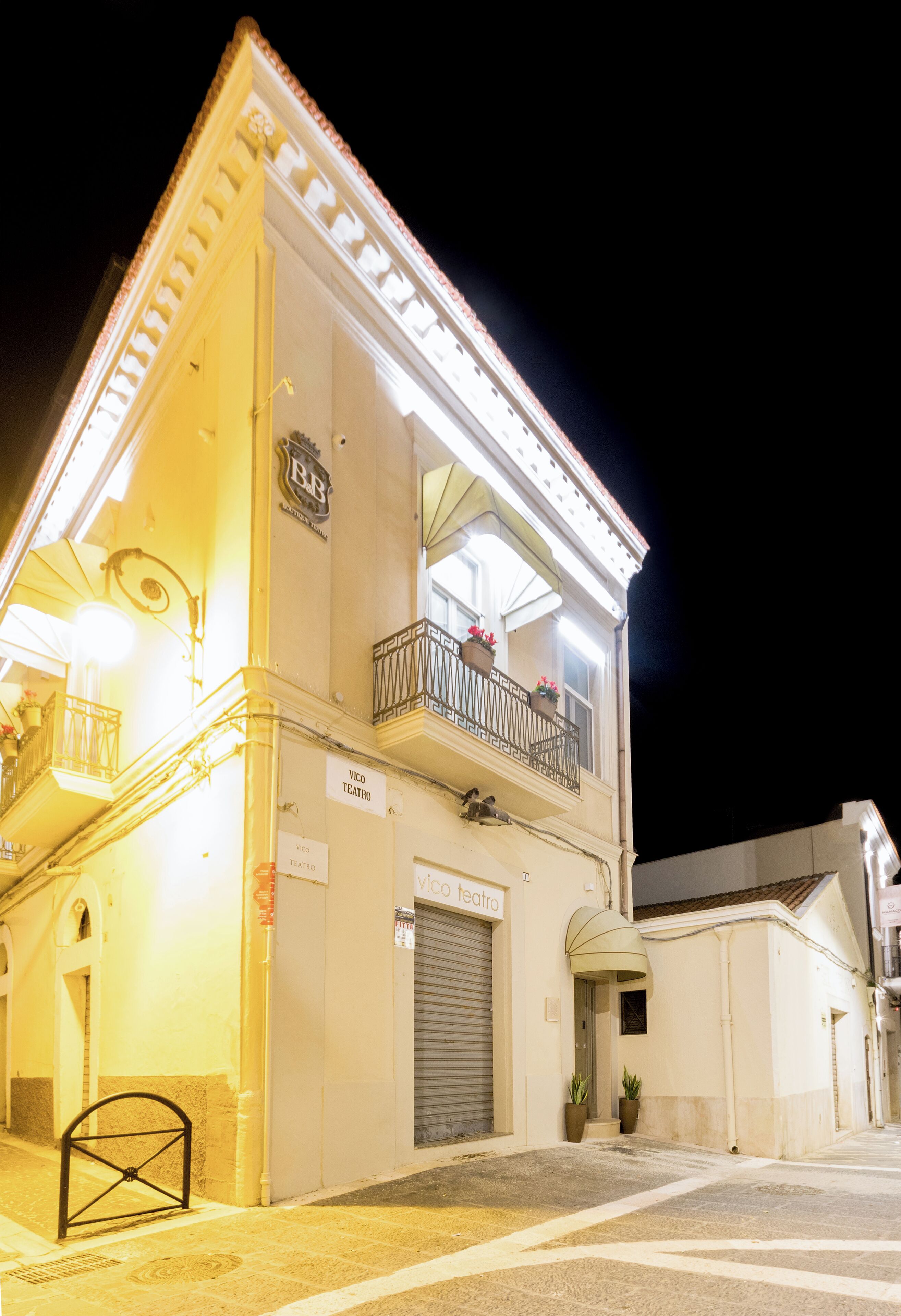 Un bâtiment à deux étages doté d’un balcon, d’une enseigne indiquant qu’il s’agit d’un théâtre, et d’une porte à volets fermés.
