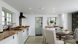Una cocina moderna con armarios blancos, encimera de madera y una zona de comedor con mesa y sillas.