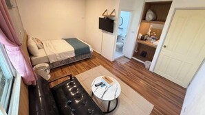 A compact room with a bed, a small seating area, a TV, and a bathroom visible through an open door. - TS Hotel (Taitung)