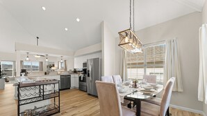 A modern kitchen with a dining area, featuring a glass table, chairs, and a hanging light fixture. - Golf Views • Central Branson • 3 King Suites (Branson)